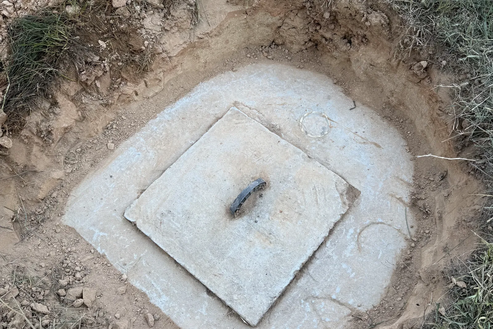 Concrete septic tank lid uncovered in red clay soil on a North Carolina property