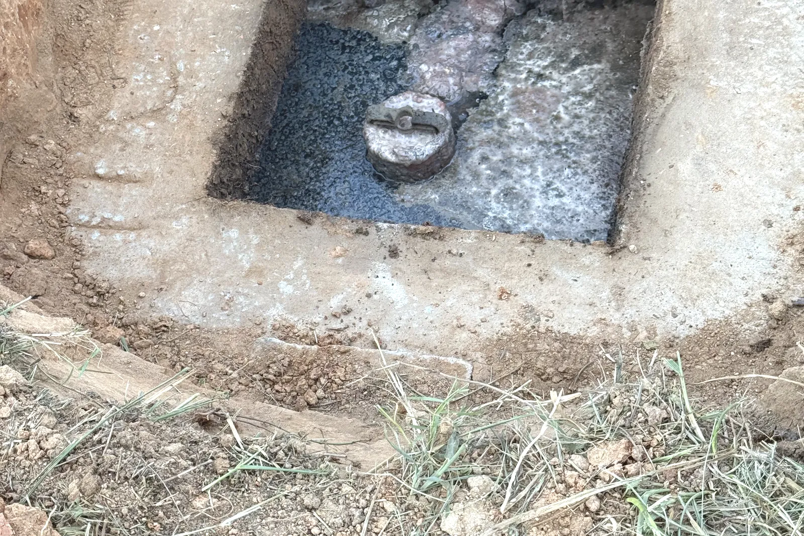 Uncovered septic tank outlet chamber with the outlet fitting and floating scum, where effluent filter cleaning happens