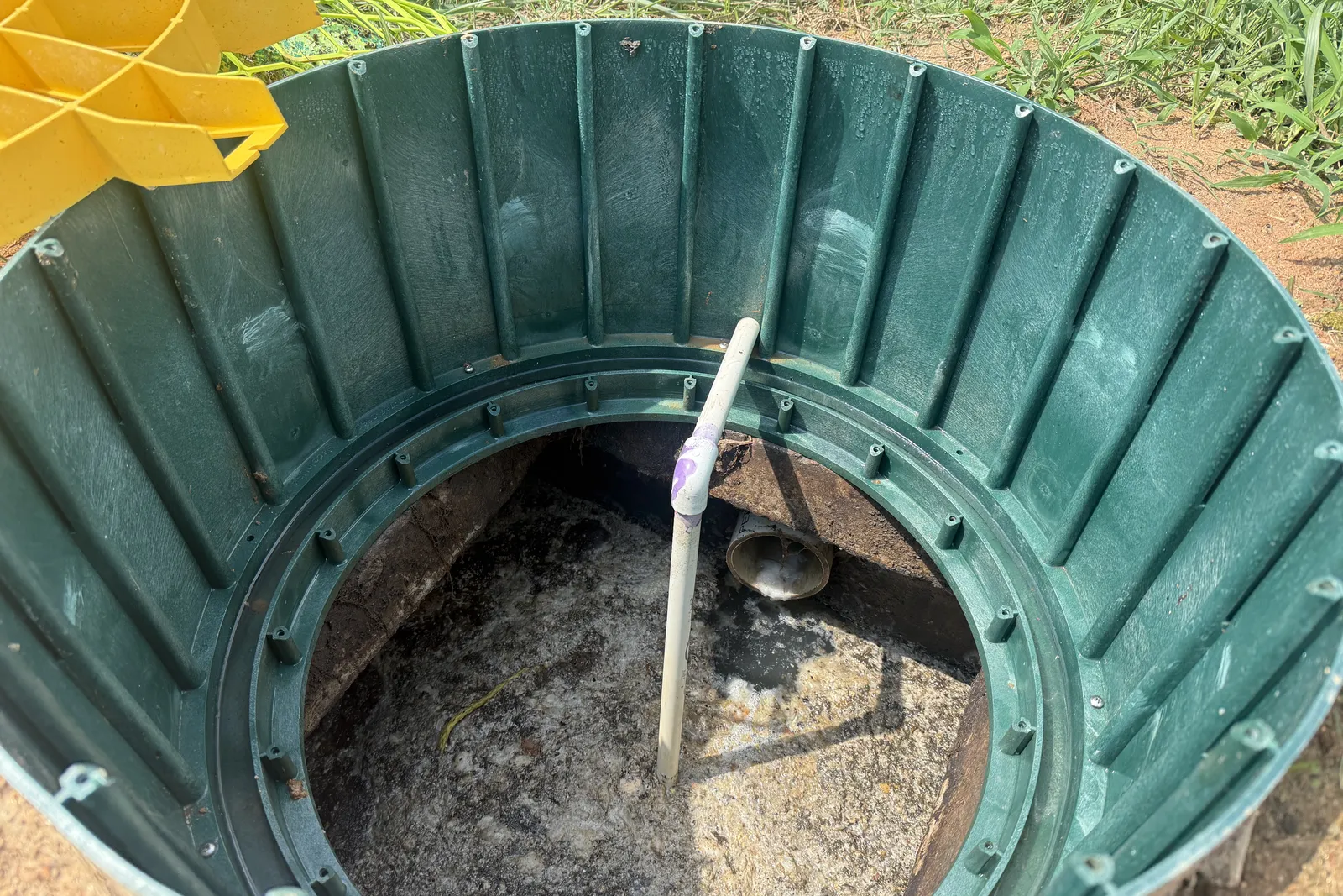 Looking into a septic tank at the crusted surface with the air line going in